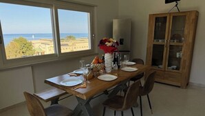 A dining area with a view of the sea, a wooden table set for four, and a cabinet with glass doors. - 2 Bedroom Apartment in PALERMO (PALERMO)