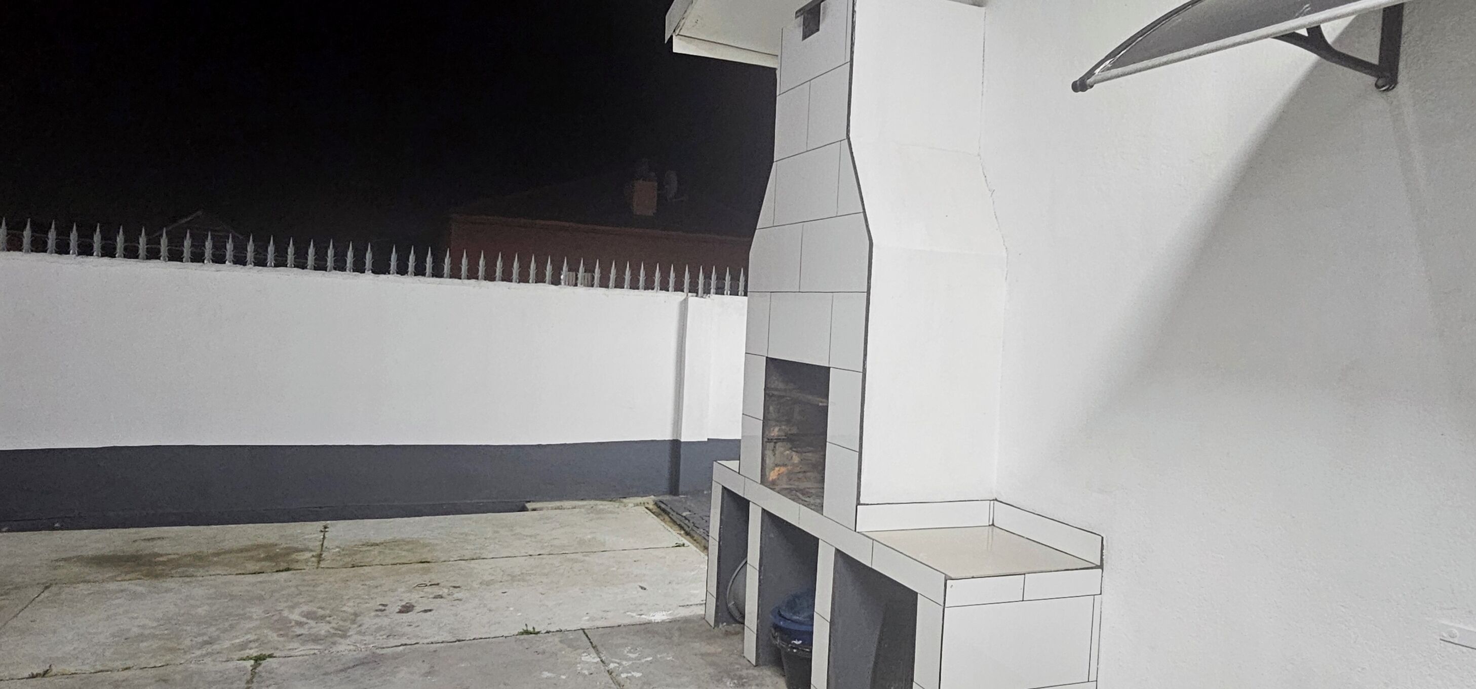 A white building with a tiled exterior and a metal railing.