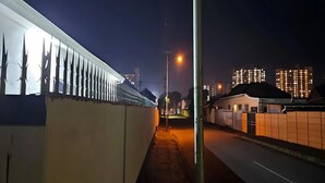 Una vista notturna di una strada, con file di edifici su un lato e un lampione in primo piano.