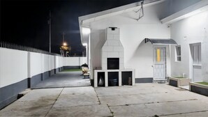Una moderna zona patio esterna con una griglia barbecue integrata, un piccolo angolo relax e una finestra con vista sui dintorni.