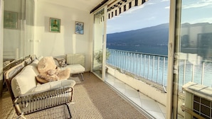 A balcony with a wicker sofa, a teddy bear, and a potted plant. - Cosy - Vue Imprenable sur le lac (Tresserve)