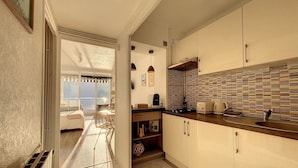 A kitchen with a tiled backsplash, a sink, and a countertop with kitchen appliances. - Cosy - Vue Imprenable sur le lac (Tresserve)