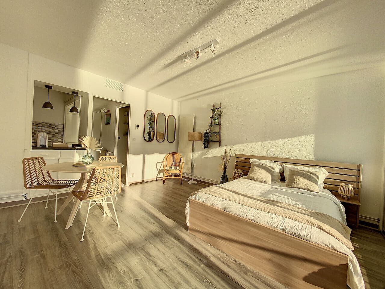 Un dormitorio con una cama de madera, una mesa de comedor con sillas, una silla y un espejo.