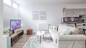 Ein modernes Wohnzimmer mit Fernseher, Sofa, Couchtisch und Kunstwerk an der Wand.