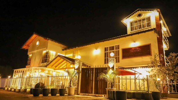 A two-story building with a gated entrance, potted plants, and a well-lit facade. - The Crosswoods Three (Kosiyakutoli)