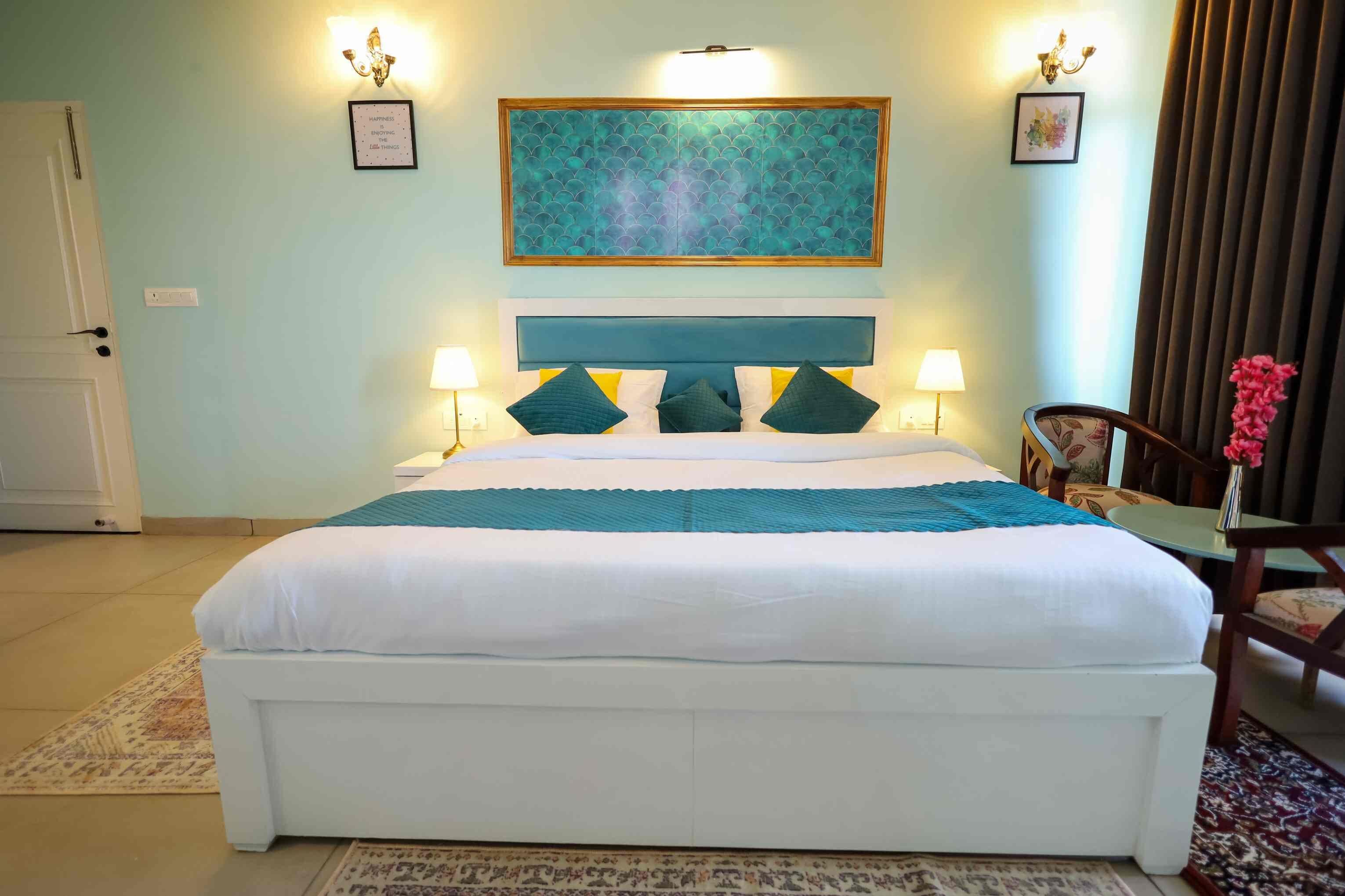 A neatly arranged bedroom with a large bed, bedside lamps, a decorative wall piece, and a chair with a vase of flowers.