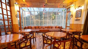 A cozy restaurant with wooden furniture, large windows, and a view of the outdoors. - The Crosswoods Three (Kosiyakutoli)