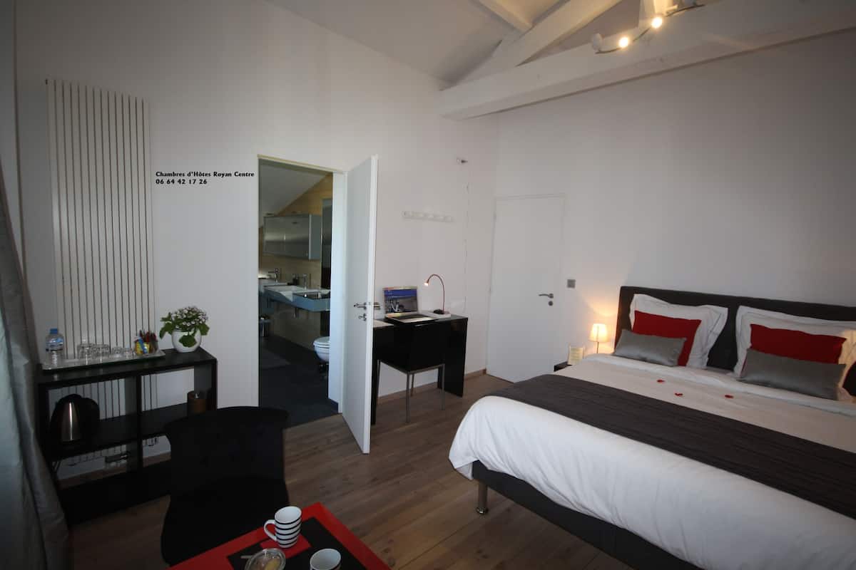 Quarto de hotel com cama, escrivaninha e vista para o banheiro.