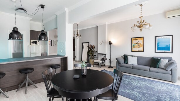 A modern living room with a grey sofa, a round dining table with chairs, and pendant lighting. - Pumpkin by halu' Lux 2BD-apartment (Thessaloniki)