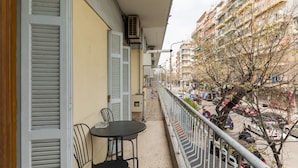 A balcony with a table and chairs, overlooking a busy street with cars and buildings. - Pumpkin by halu' Lux 2BD-apartment (Thessaloniki)
