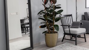 A modern living room with a large mirror, a potted plant, a floor lamp, and a chair. - Pumpkin by halu' Lux 2BD-apartment (Thessaloniki)