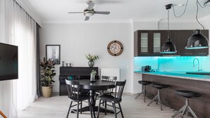 A modern kitchen with a central island, bar stools, a dining table with chairs, a ceiling fan, and a clock on the wall. - Pumpkin by halu' Lux 2BD-apartment (Thessaloniki)