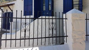 A white building with blue shutters and a metal fence. - Beautiful, traditional Greek home with stunning views. (Glossa)