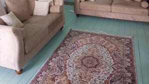 A room with two beige sofas, a patterned rug, a teal door, and a window with curtains. - Beautiful, traditional Greek home with stunning views. (Glossa)