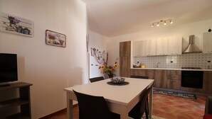 A modern kitchen with wooden cabinets, a white countertop, and a built-in oven. - Vincenzo House (Castelluzzo)