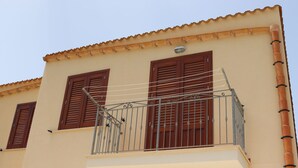 A building with a balcony, brown shutters, and a tiled roof. - Vincenzo House (Castelluzzo)