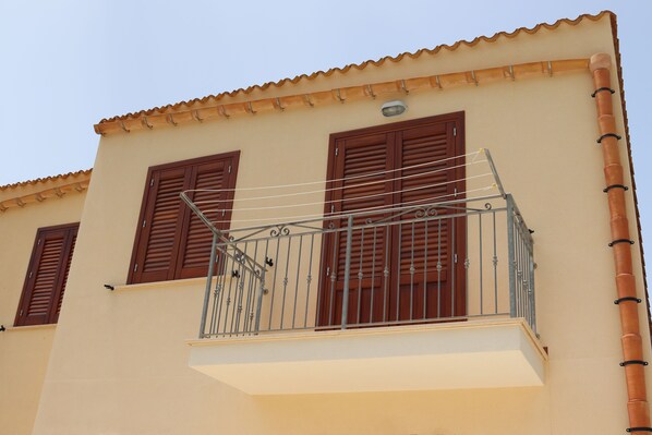 Un bâtiment doté d’un balcon, de volets bruns et d’un toit recouvert de tuiles.