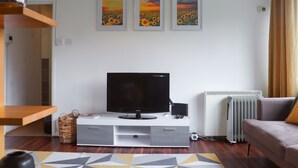 A modern living room with a flat-screen TV on a white entertainment unit, a grey sofa, and a radiator. - Lovely 1-bed Apartment in Birmingham (Birmingham)