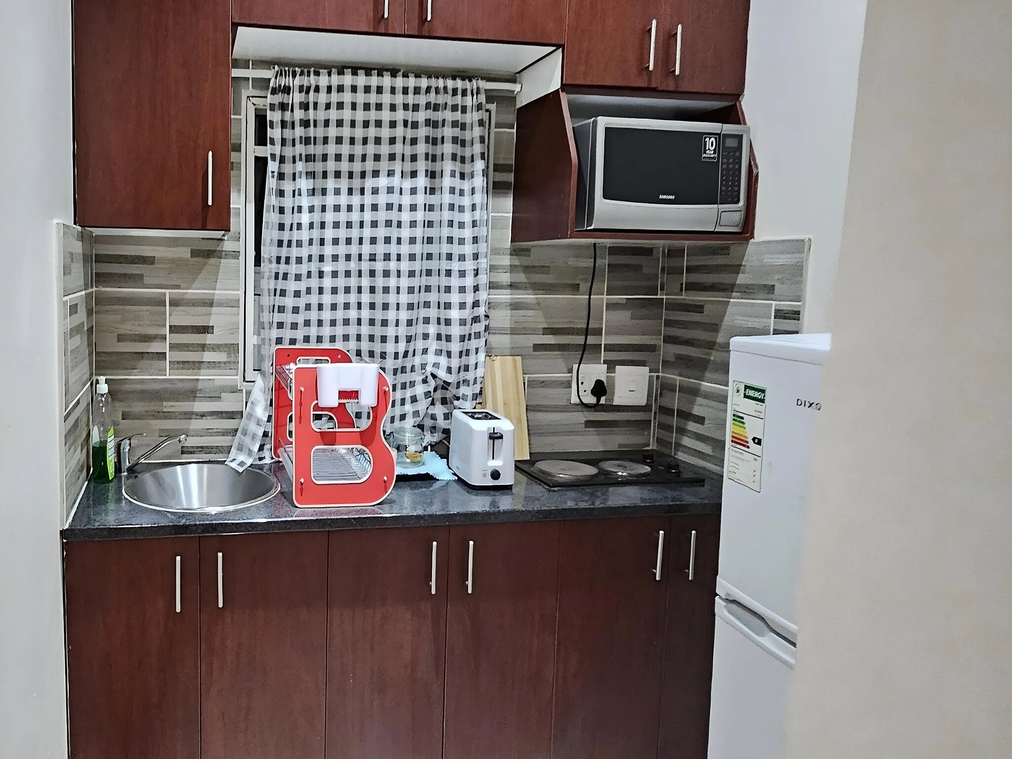 A compact kitchen with a microwave, toaster, and sink.