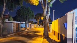 A nighttime street scene with a sidewalk, trees, and a building with a yellow and gray facade. - Goshen Lodge Spencer (Cape Town)