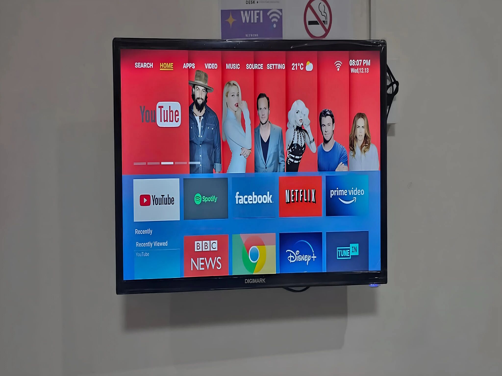 Un téléviseur à écran plat fixé au mur, affichant différents logos et icônes de services de diffusion en continu.