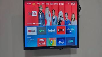 Un téléviseur à écran plat fixé au mur, affichant différents logos et icônes de services de diffusion en continu.