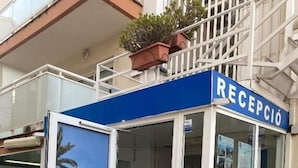 A reception area with a glass door, a blue sign above it, and a poster advertising a hostel. - HOSTAL TAHITI RS (Salou)
