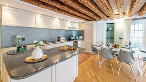 Una cocina moderna con encimera de granito, armarios blancos y techo de madera.
