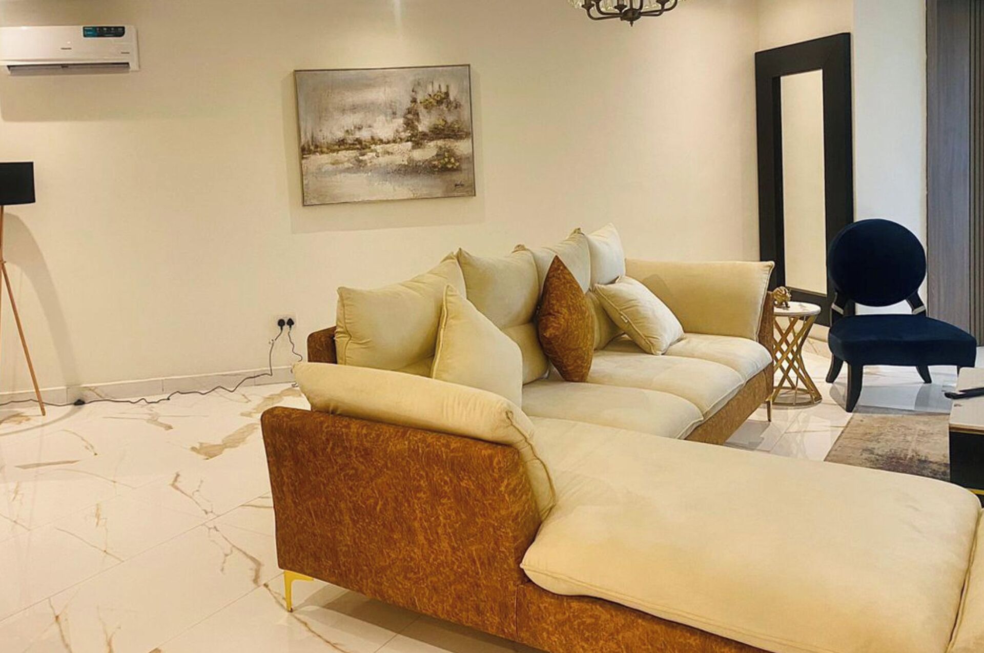 A modern living room with a sofa, a chair, and a painting on the wall.
