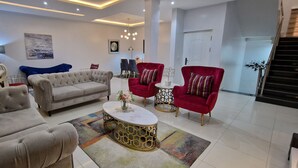 A modern living room with a grey sofa, red armchairs, and a coffee table. - Luxury 3-bed House in Gated Estate With Pool Lekki (Lekki)