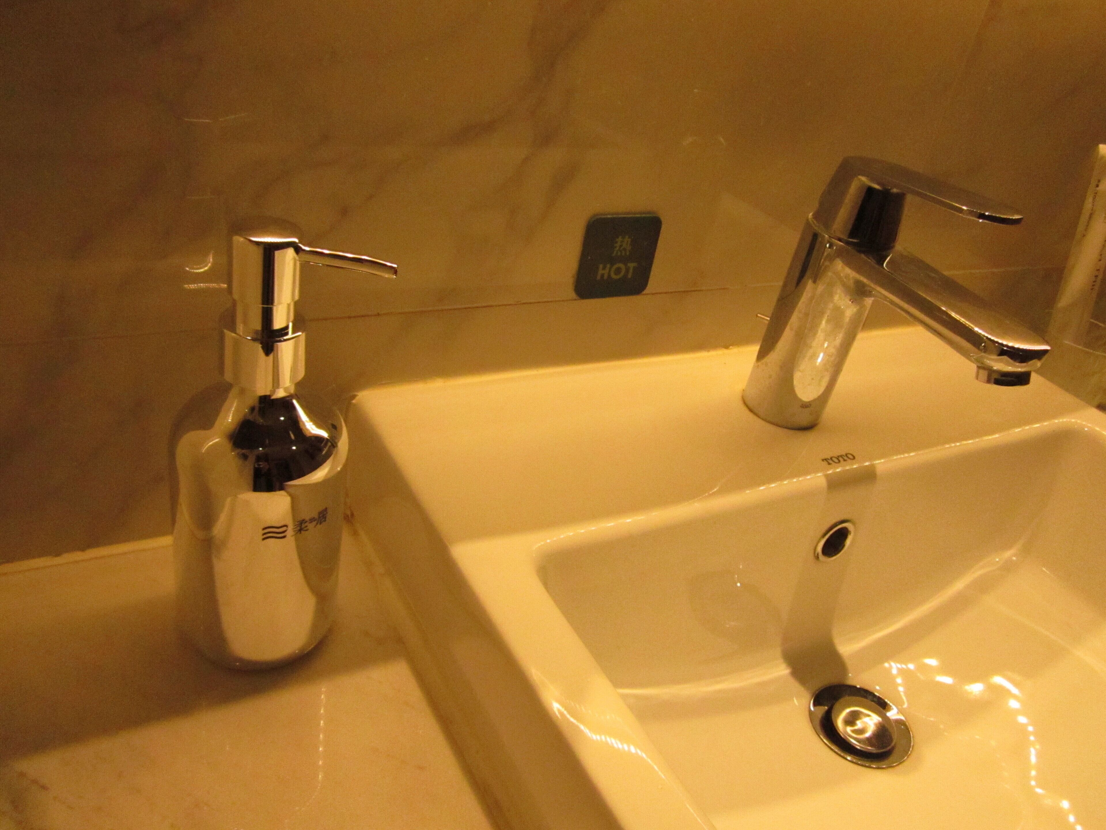 Un lavabo de salle de bain avec un robinet chromé et un distributeur de savon.