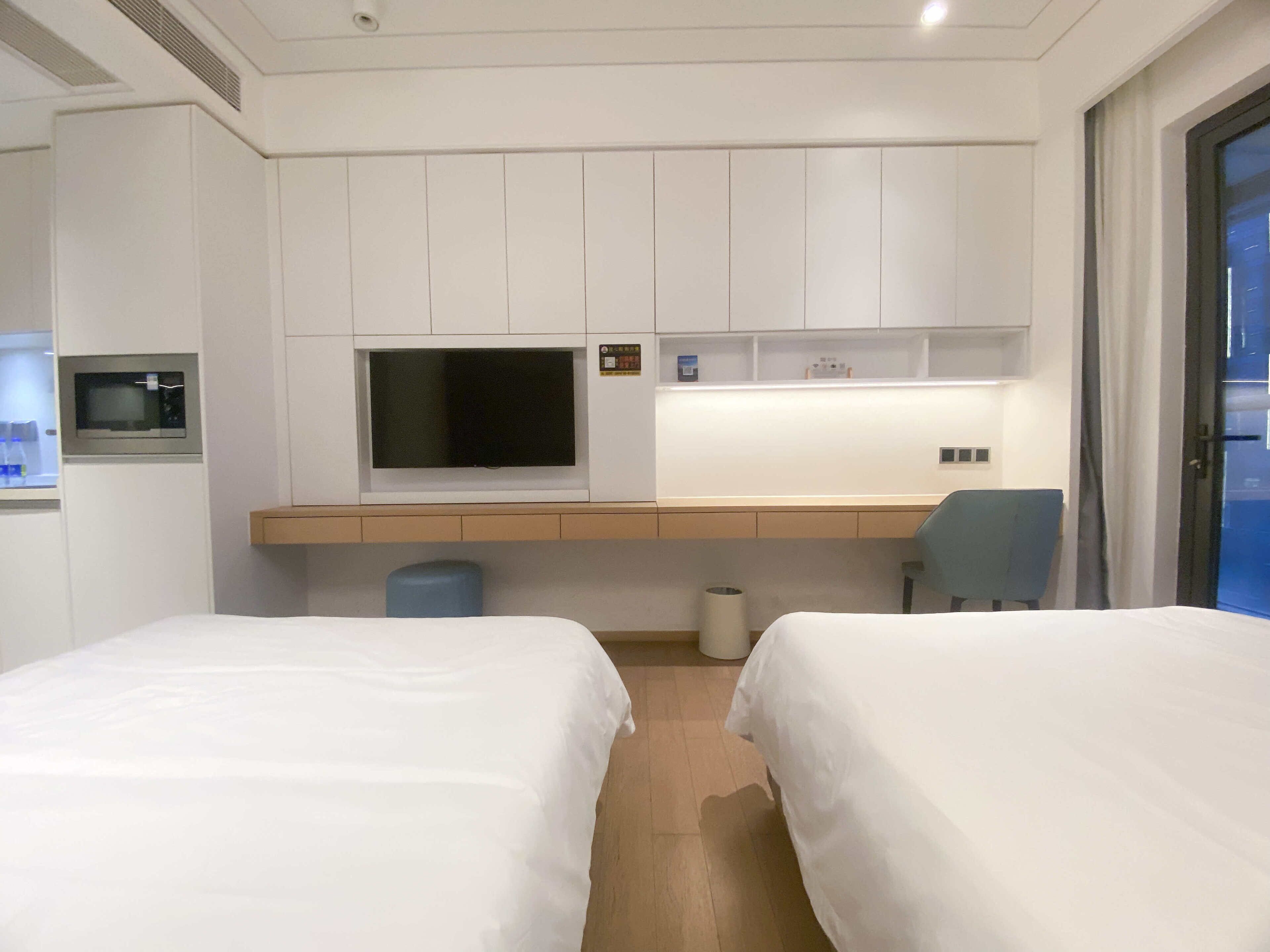 Una habitación de hotel con dos camas, televisión, escritorio y una silla.