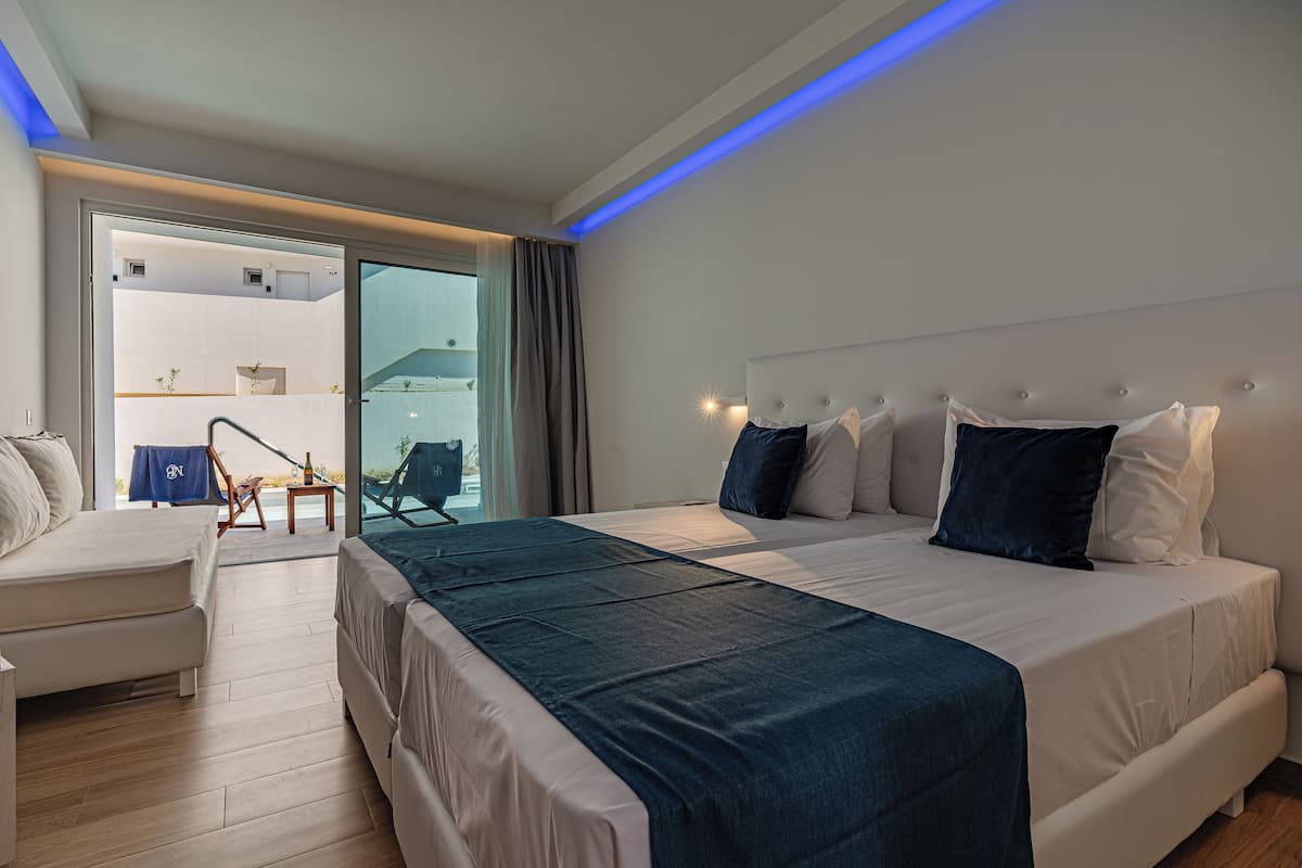 A modern hotel room with a large bed, a sofa, and a balcony with a view.