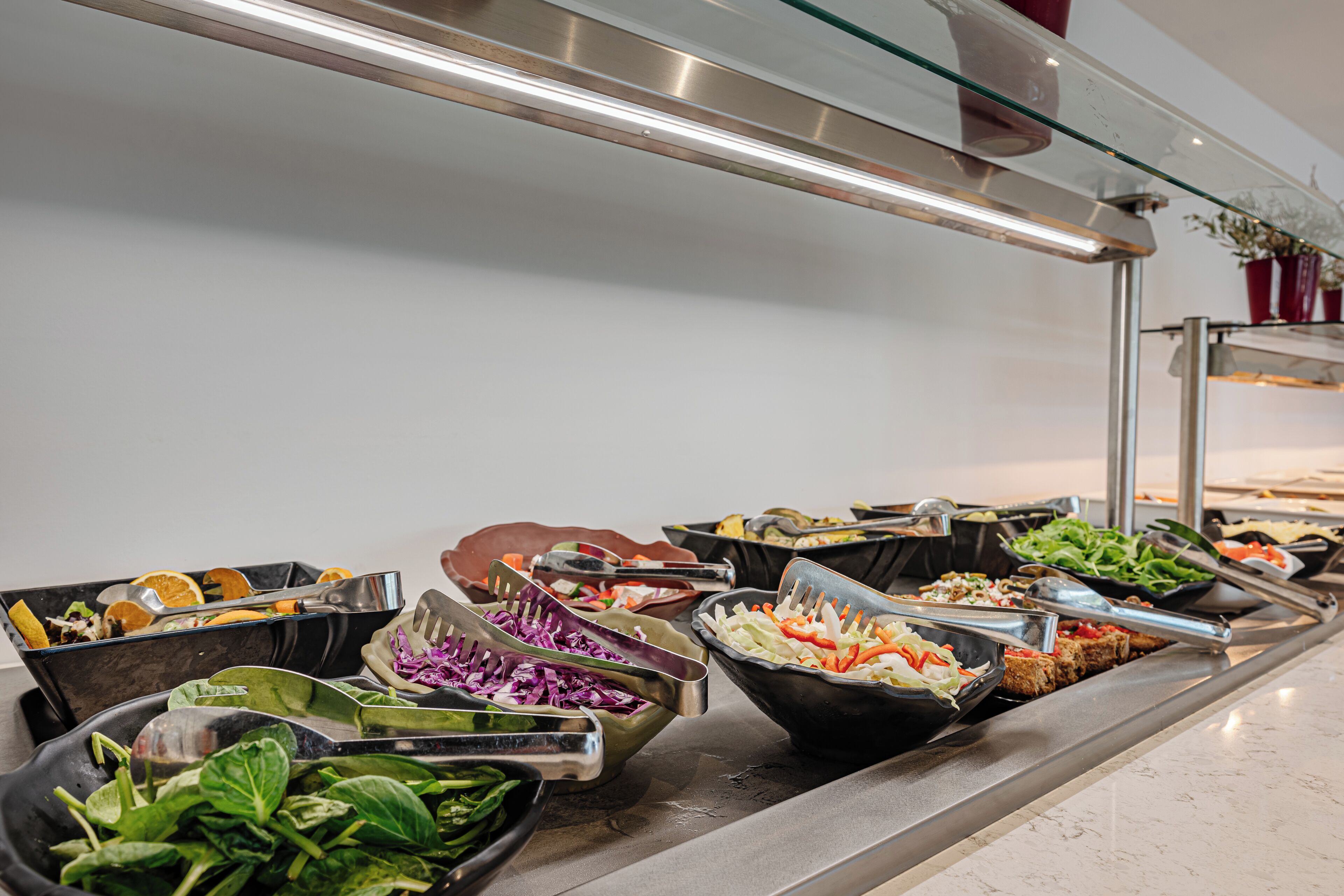 A buffet with various food options including salads, vegetables, and bread.