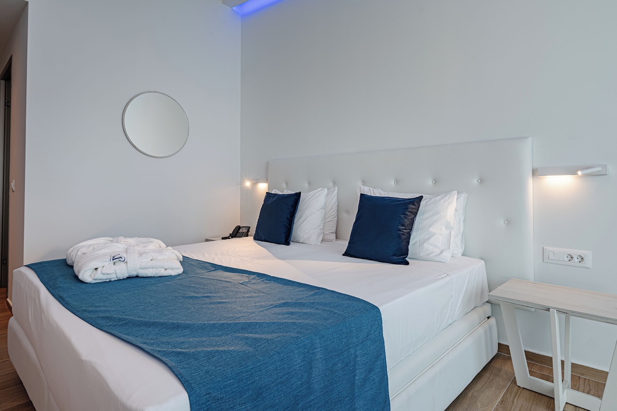 A modern bedroom with a large bed, a bedside table, and a wall-mounted light fixture.