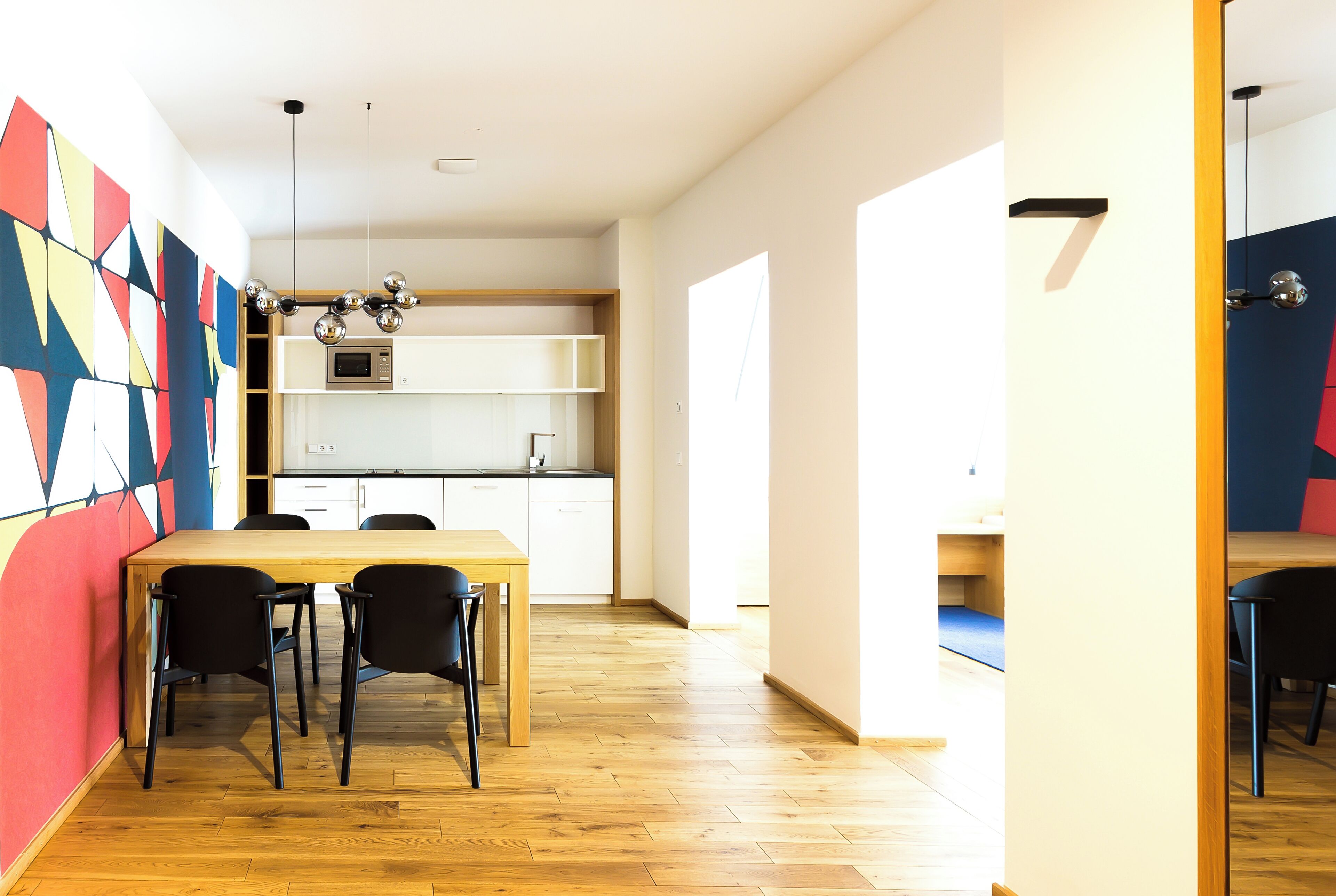 Una cocina moderna con armarios blancos, una mesa de comedor de madera y sillas negras.