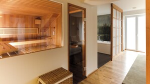 Un interior moderno con sauna de madera, una habitación con paredes de cristal y una puerta corredera tradicional.