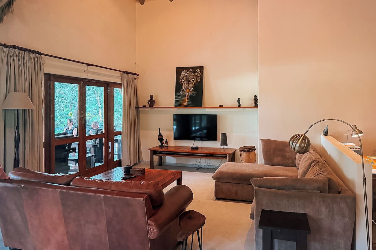 A living room with a sofa, a coffee table, a TV, and a painting on the wall.