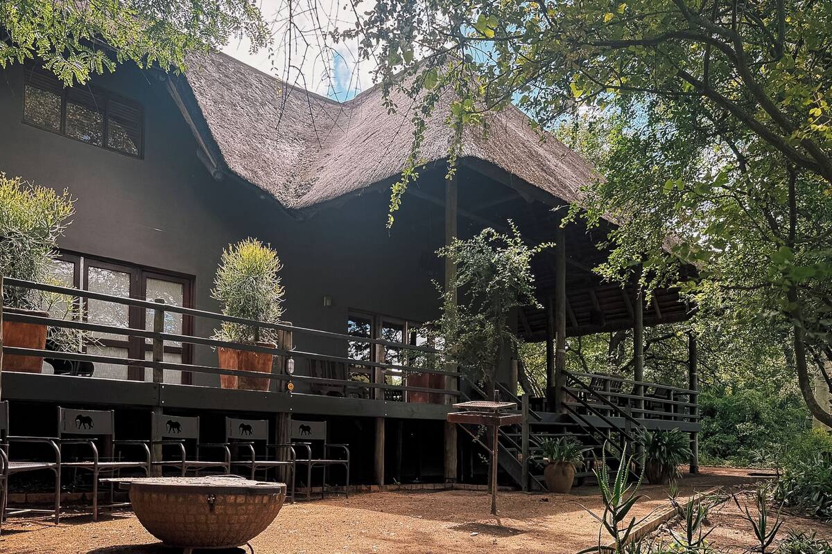 A building with a thatched roof, outdoor seating, and potted plants.