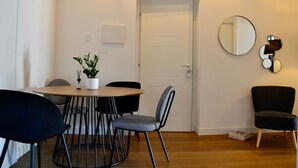 A dining area with a round table, black and white checkered chairs, a potted plant, and a mirror on the wall. - Olivuzza 27 (Palermo)