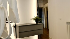 A modern bathroom with a wooden floor, a grey vanity, a mirror, and a potted plant. - Olivuzza 27 (Palermo)