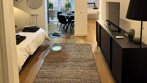 A modern room with a bed, a desk, a TV, and a dining area with chairs and a table. - Olivuzza 27 (Palermo)