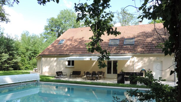 Una casa con piscina, muebles de exterior y un patio cubierto.