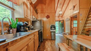 A wooden cabin kitchen with a refrigerator, stove, and sink. - 2Q Cabin near Leesville Lake ~Pets welcome~ (Carrollton)