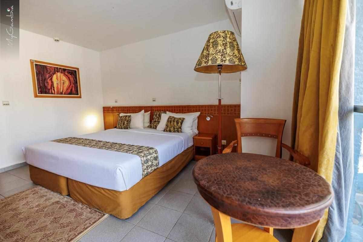 Une chambre d’hôtel avec un lit, un bureau, une chaise, une lampe et un tableau au mur.