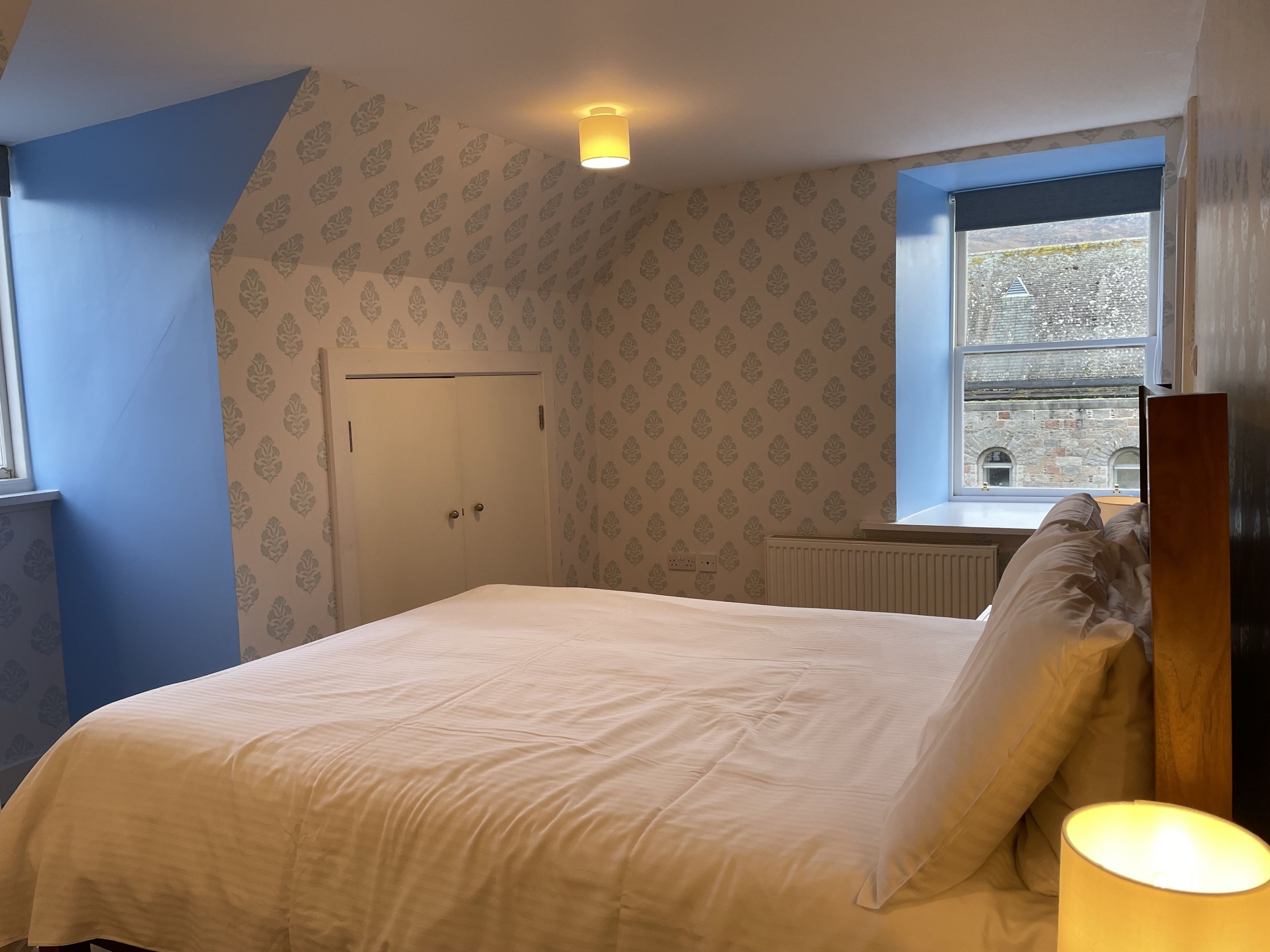 A bedroom with a bed, a window, and a radiator.