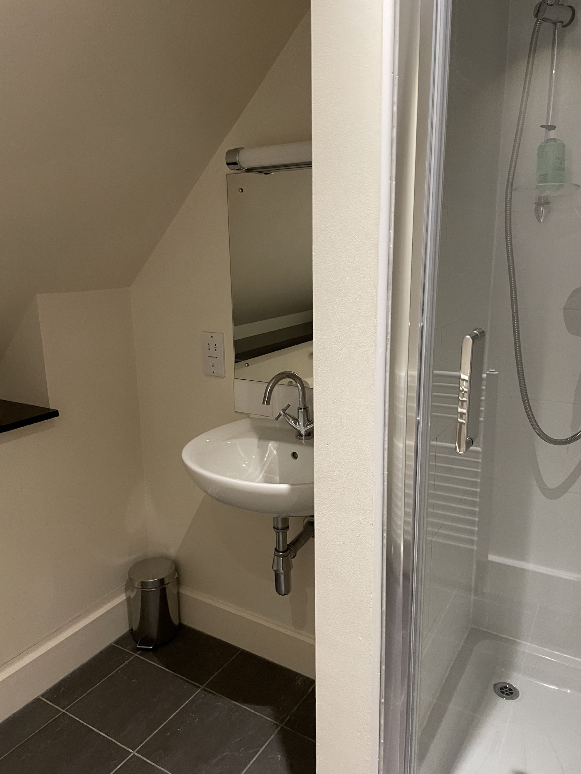 A bathroom with a white sink, a mirror, and a glass-enclosed shower.