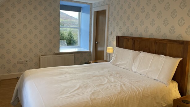 Un dormitorio con una cama grande, una ventana con vistas y papel tapiz estampado.