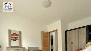 Een hotelkamer met een bed, een bureau, een kledingkast en een schilderij aan de muur.