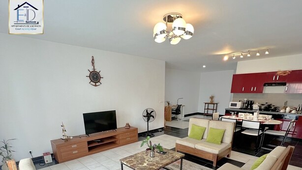 Een moderne woonkamer met een zithoek, een salontafel, een televisie en een eethoek.